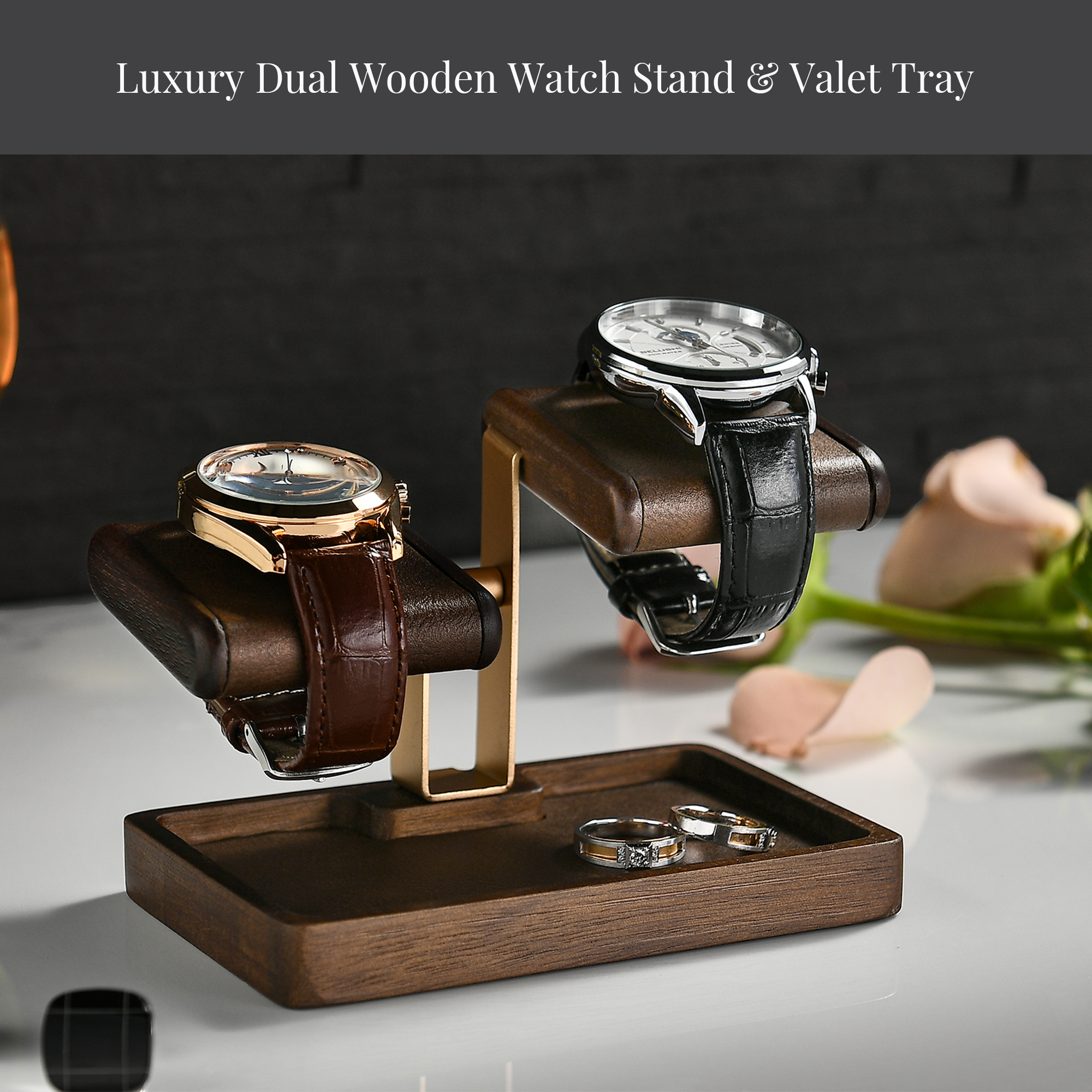 A luxury dual wooden watch stand with two watches on display, one with a brown leather strap and the other with a silver metal strap, placed on a wooden tray.