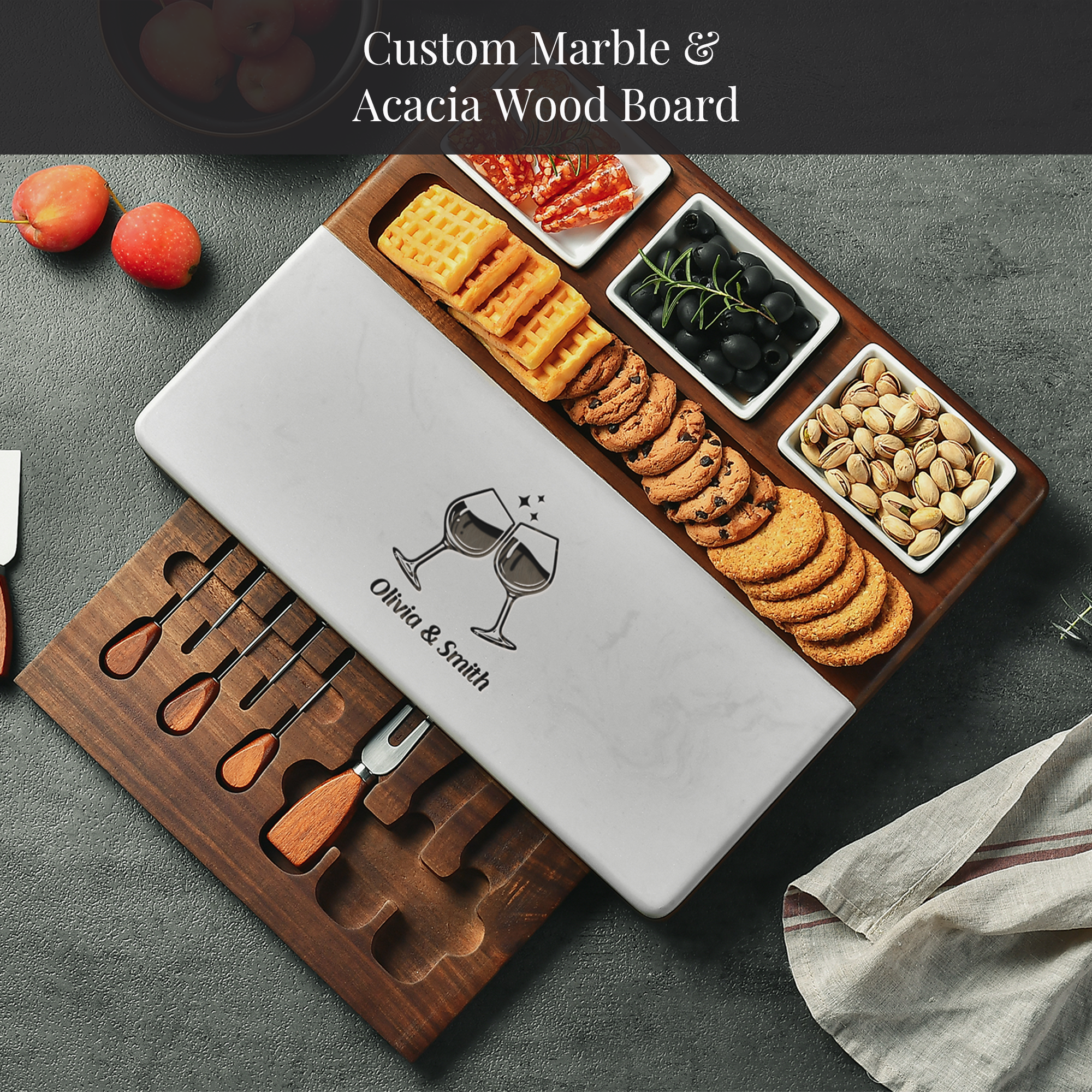 A wooden serving board with a marble top, displaying an assortment of snacks and crackers, as well as a knife set.