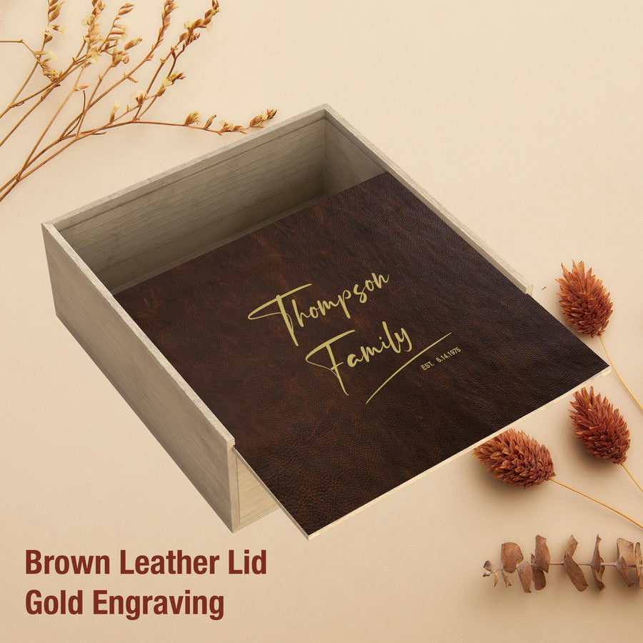 a brown leather lid with gold engraving, placed on a beige background with dried flowers and pine cones.