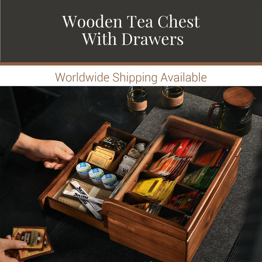 a wooden tea chest with drawers, containing various tea bags and other tea-related items. The chest is placed on a table, and there are two cups visible in the scene.