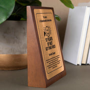 a plaque on a table with a potted plant in the background