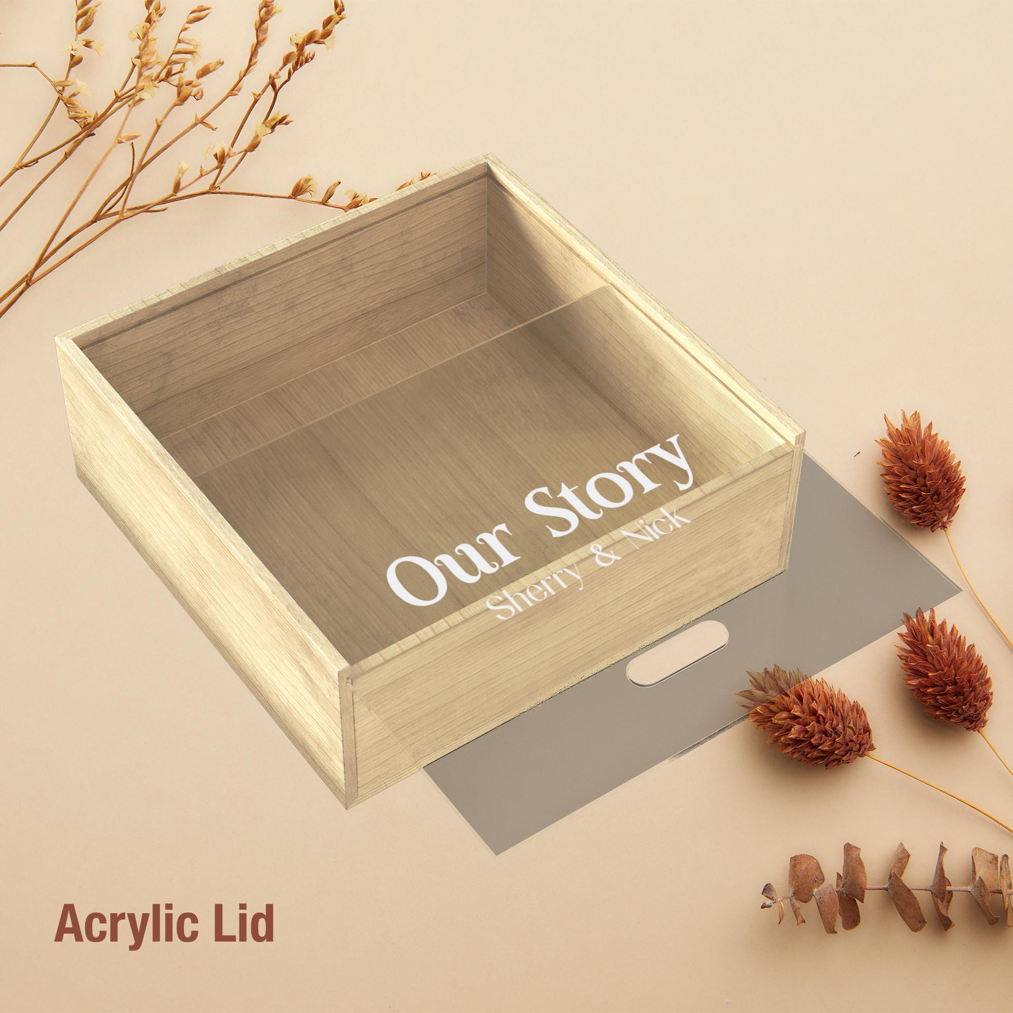 a wooden box with a clear lid, placed on a beige background. The box has the text "Our Story" written on it, and there are dried flowers and pine cones nearby.
