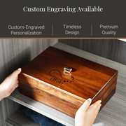A person's hands are holding a wooden box with a custom engraving on it, which features the name "Olivia" and a heart symbol. The box is described as having custom engraving available, suggesting it is a personalized item.