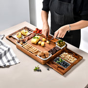 A person is arranging a wooden platter with various food items on a table.
