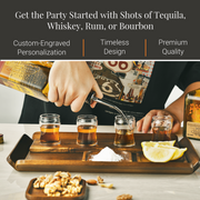 a person pouring shots of tequila, whiskey, rum, and bourbon into small glasses, with garnishes like nuts and lemon slices. The person is wearing a black shirt.