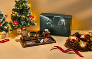 a Christmas-themed display with a small Christmas tree, a gift box, and various accessories such as a watch, sunglasses, and a wreath.