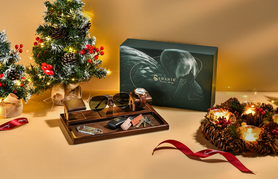 a Christmas-themed display with a small Christmas tree, a gift box, and various accessories such as a watch, sunglasses, and a wreath.