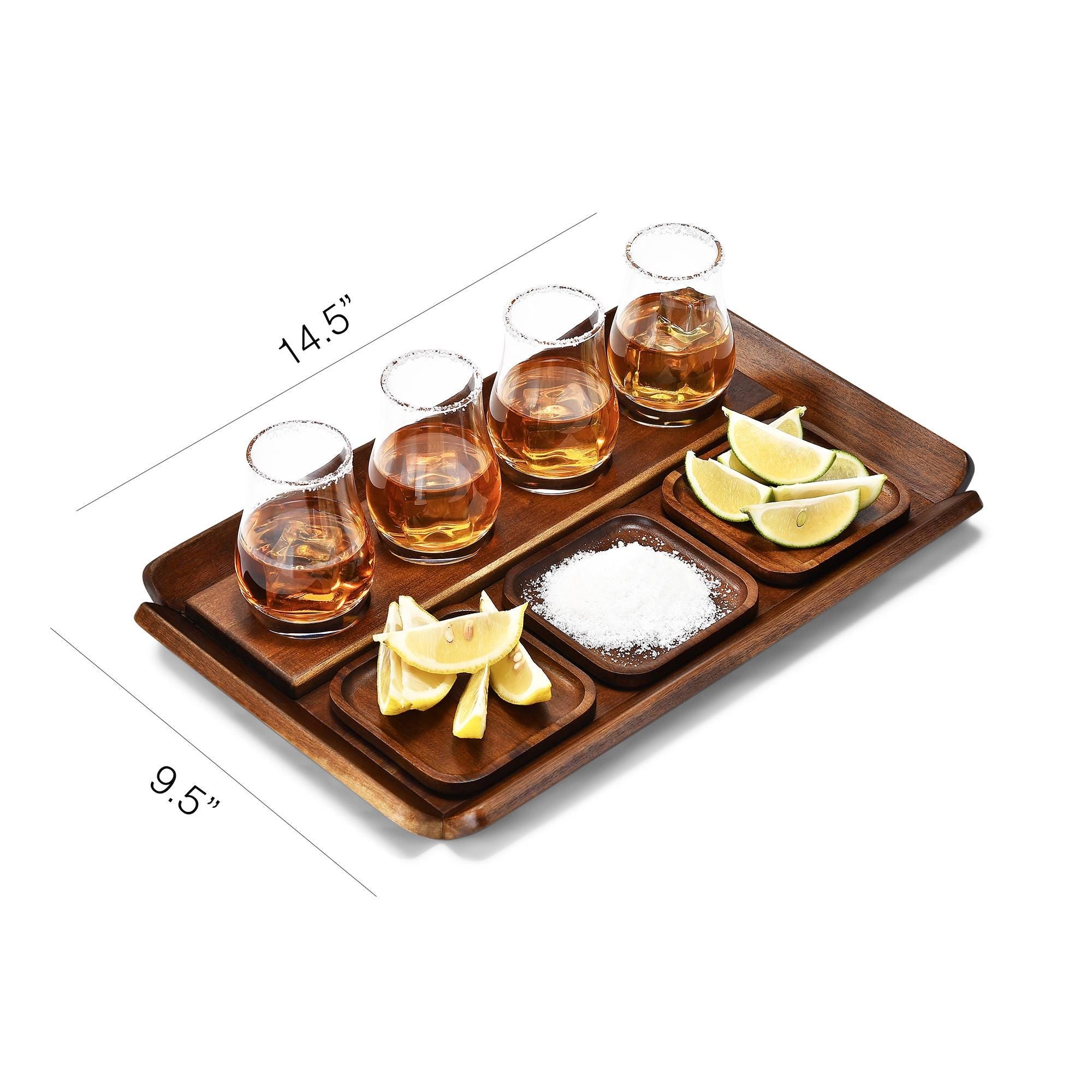 A wooden tray with four glasses of amber-colored liquid, likely whiskey, and a small bowl of lemon wedges and salt.