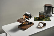a collection of watches and a coffee pot on a white table.