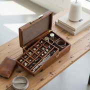 A wooden jewelry box with compartments containing various pieces of jewelry, such as rings, bracelets, and necklaces, placed on a wooden table.
