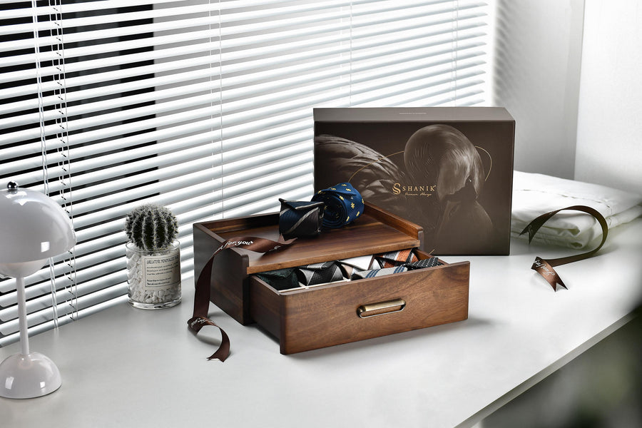 a wooden drawer with a cactus plant and a small glass container on a white desk, along with a brown box with a picture of a person's face on it.