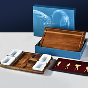 a wooden tray with four compartments, a wooden box with a lid, and a set of gold-colored serving utensils.