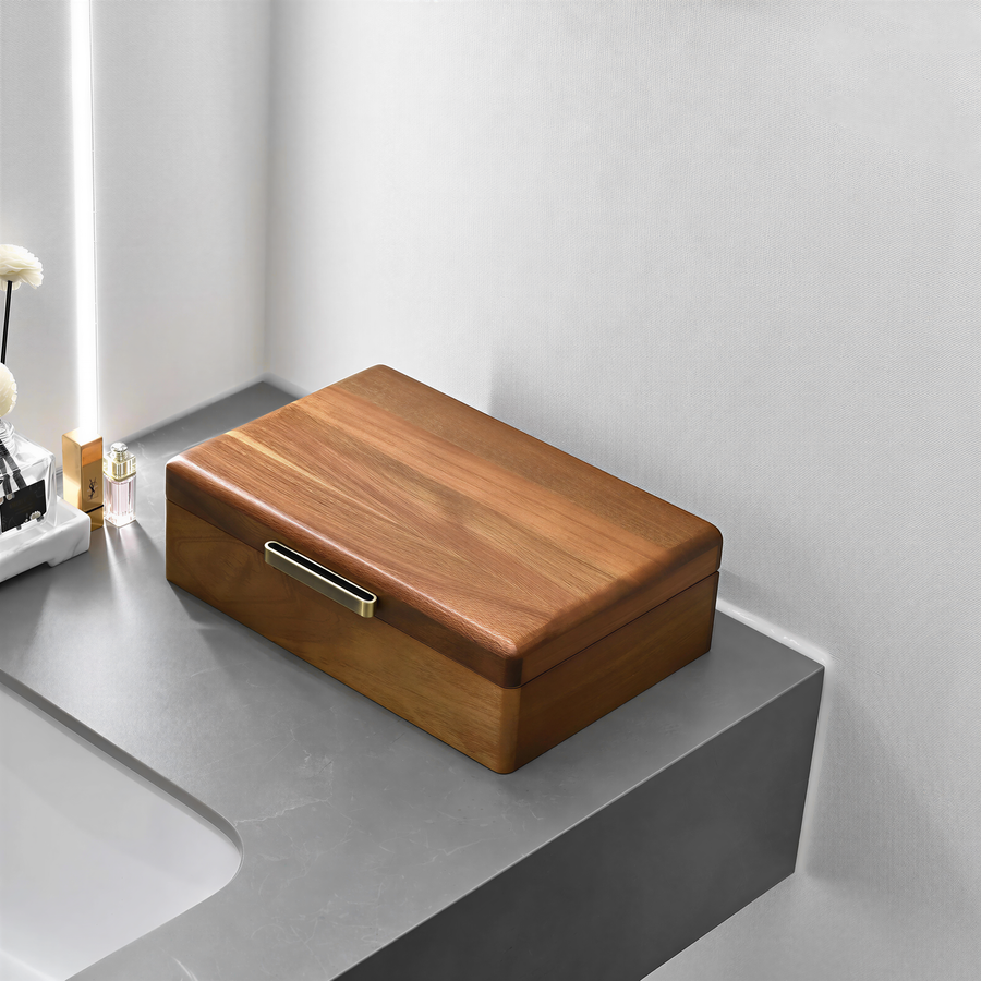 A wooden box with a metal handle sits on a gray countertop in a bathroom setting.