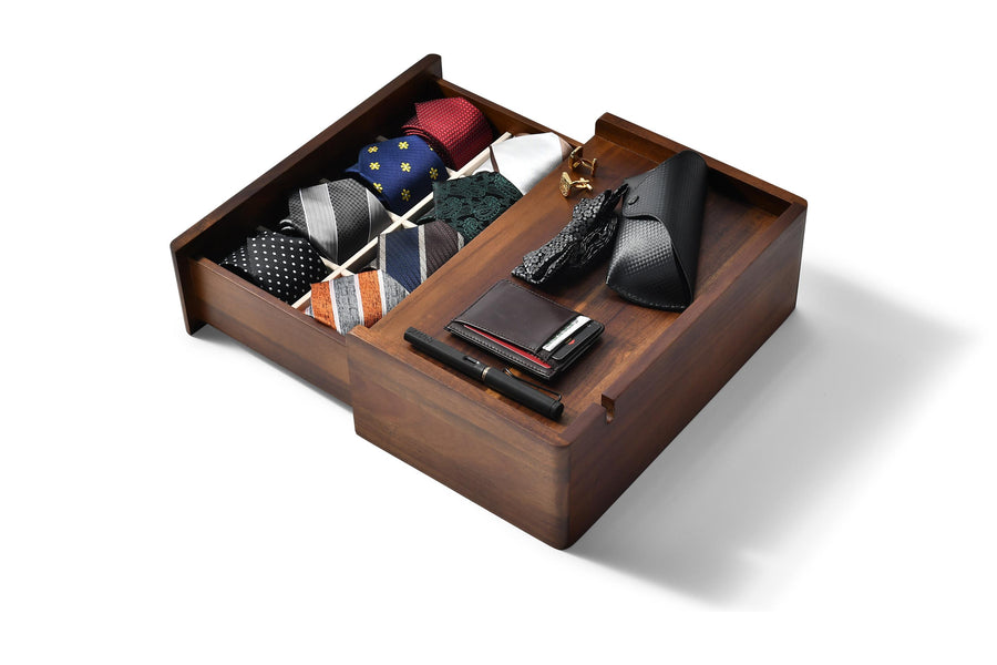 a wooden drawer with various accessories neatly organized inside, including ties, a wallet, and a pen.