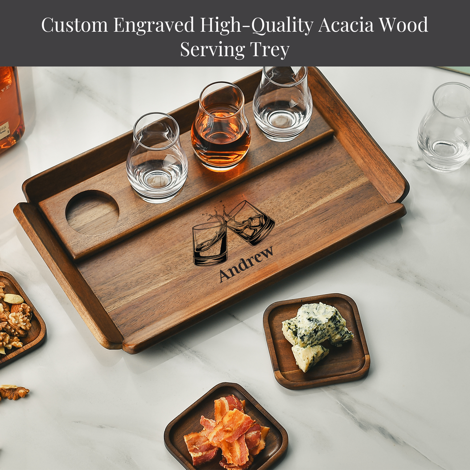 A wooden serving tray with a custom engraved design, featuring a pair of glasses and a name, Andrew, on it. The tray is accompanied by various food items, including a plate of bacon, a plate of cheese, and a plate of nuts.