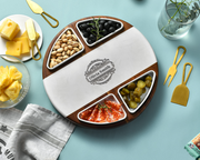 a round wooden platter with a white and brown design, containing various food items such as cheese, nuts, olives, and sliced meats, arranged on a blue background.