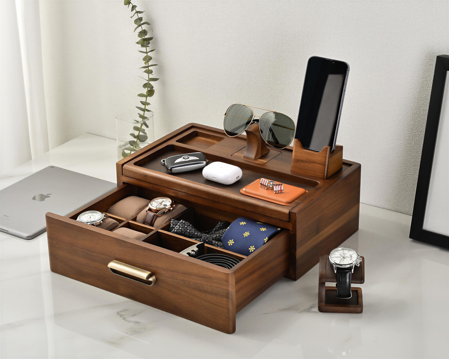 A wooden drawer organizer with multiple compartments, displaying various accessories such as a watch, sunglasses, and a phone.
