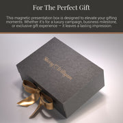a gray gift box with a gold ribbon tied around it, sitting on a white surface.