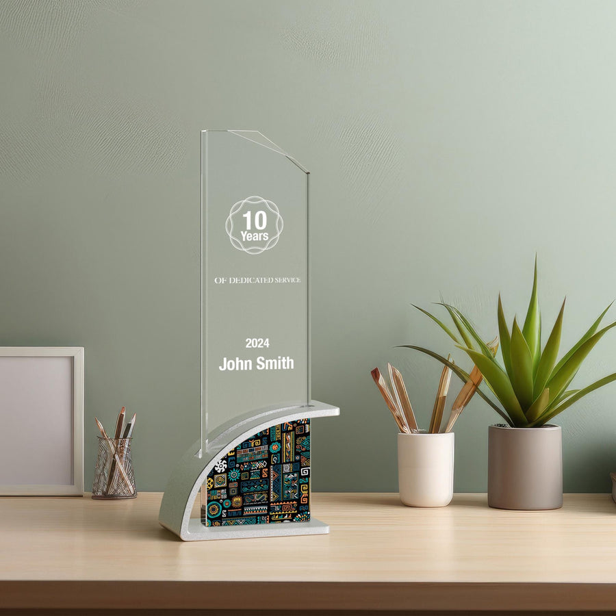 10 Years of Dedicated Service award for John Smith, 2024, crafted from optic crystal with a distinctive circuit board pattern base, positioned on a desk surrounded by office essentials and green plants.