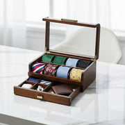 A wooden tie holder with multiple compartments, displaying a variety of colorful ties, is placed on a white marble surface.