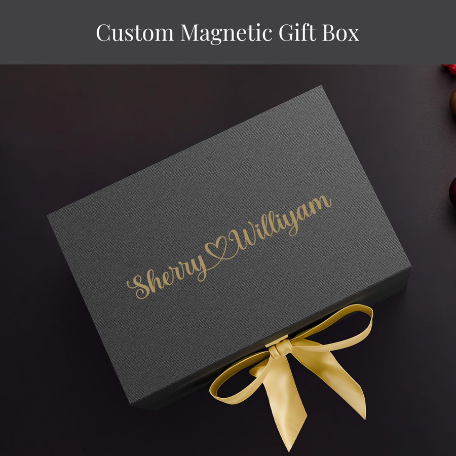 A gray gift box with a gold ribbon tied around it, placed on a dark surface.
