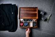 A wooden box with a drawer, containing a variety of ties, is shown in the image.