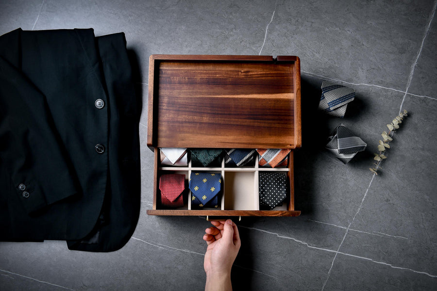 A wooden box with a drawer, containing a variety of ties, is shown in the image.