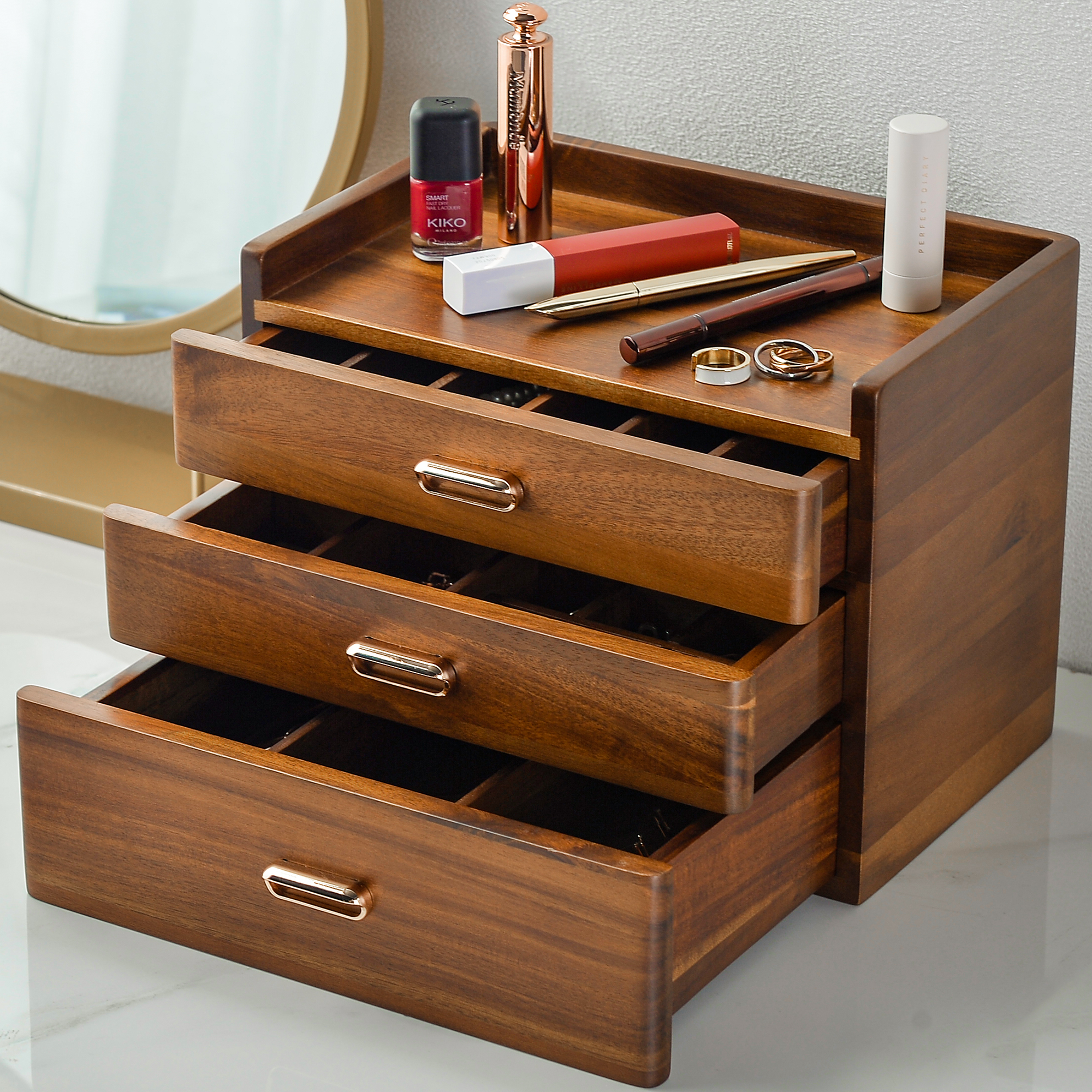 A wooden drawer organizer with three open compartments, containing various makeup and beauty products such as lipsticks, eyeshadow palettes, and a toothbrush.