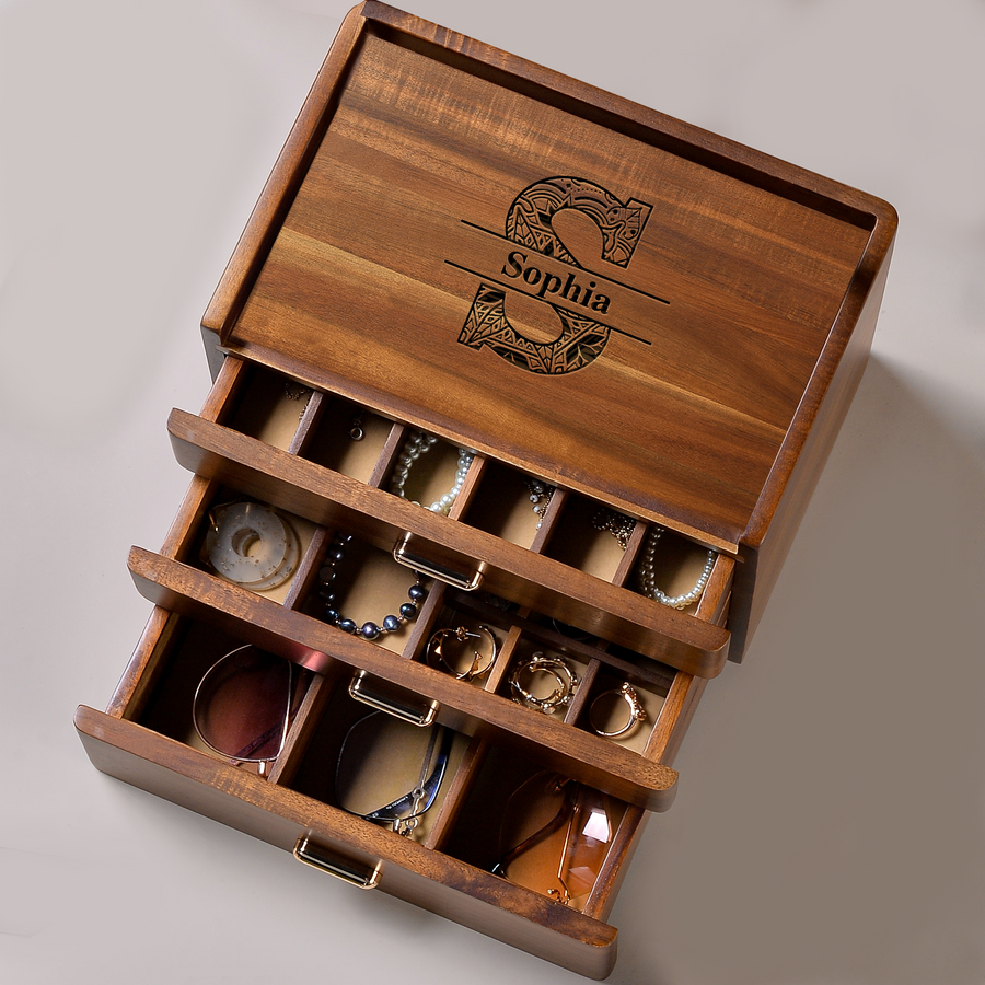 A wooden jewelry box with three compartments, each containing various pieces of jewelry such as necklaces, bracelets, and earrings. The name "Sophia" is engraved on the lid of the box.