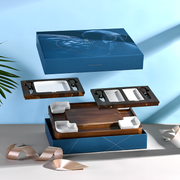 a wooden tray with a blue box above it, and there is a ribbon on the table.