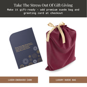 a maroon satin gift bag with a gold ribbon, a black and gold card with a floral design, and a black and gold card with a message about gift-giving.
