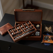 A wooden jewelry box containing various accessories, including rings, necklaces, and keys, placed on a black surface.