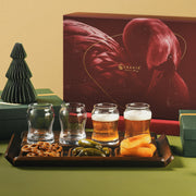 a tray with three glasses of beer, a plate of snacks, and a decorative tree, all set against a red background.