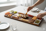 A person is serving food from a wooden platter on a table, which contains various snacks and appetizers.