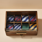 A wooden drawer with nine compartments, each containing a different colored tie.