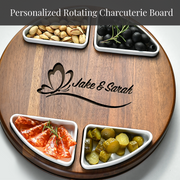 A wooden serving board with four compartments containing various types of food, including nuts, olives, pickles, and sliced meats.