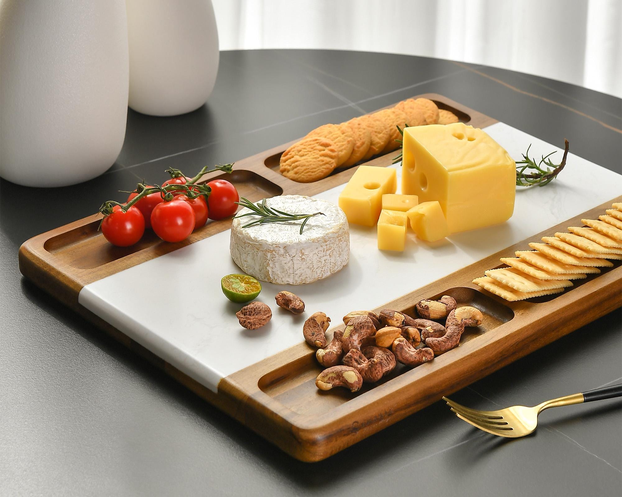 a tray with cheese, crackers, tomatoes, nuts and cheese