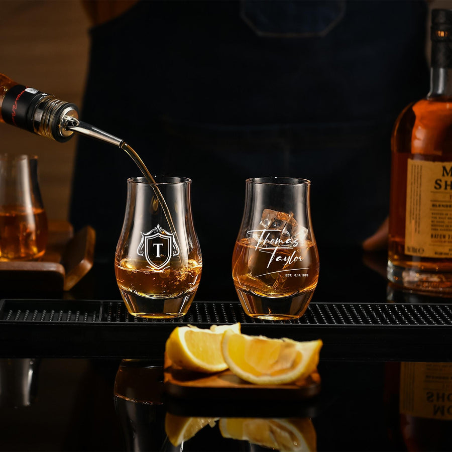 a bartender pouring a drink into a glass, with a bottle of whiskey and a lemon wedge nearby.