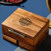 A wooden box with a decorative embossed nameplate, sitting on a blue surface.