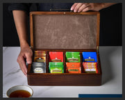 a person holding a wooden box filled with different types of tea